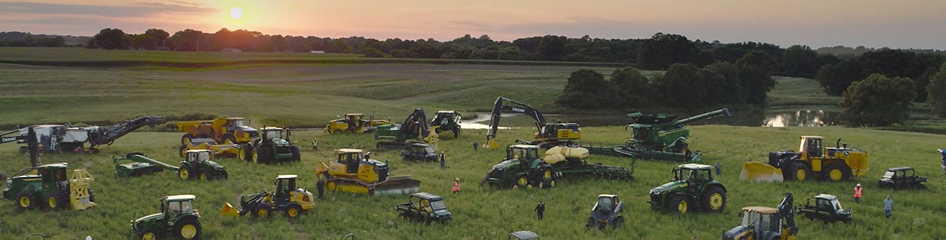 人们在一片空旷的区域穿行在多款 John Deere 设备之间。